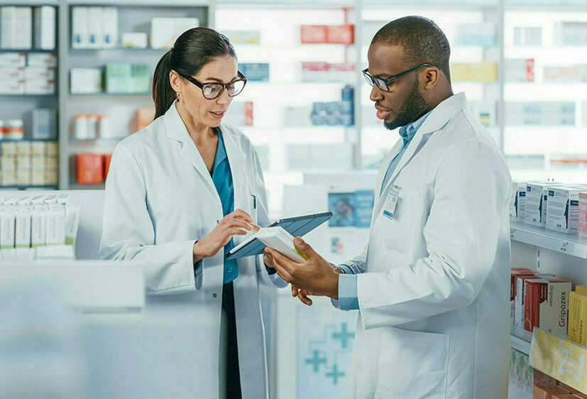 Caucasian Female Pharmacist talking to an African American Male Pharmacist in a pharmacy.